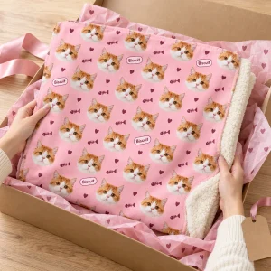 Hands unwrapping the Cat Face Pattern Blanket from a kraft gift box