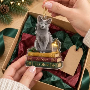 Hands unwrapping the Cat Mom Bookstack Christmas Ornament from a kraft gift box
