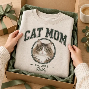 Hands unwrapping the Cat Mom Varsity Sweatshirt from a kraft gift box