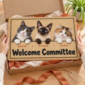 Hands unwrapping the Cat Welcome Committee Peeking Doormat from a kraft gift box