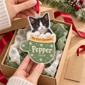 Hands unwrapping the Kitten First Christmas Mitten Ornament from a kraft gift box