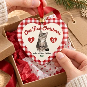 Hands unwrapping the Our First Christmas With Cat Heart Ornament from a kraft gift box
