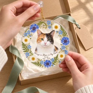 Hands unwrapping the Pressed Wildflower Cat Memorial Suncatcher from a kraft gift box